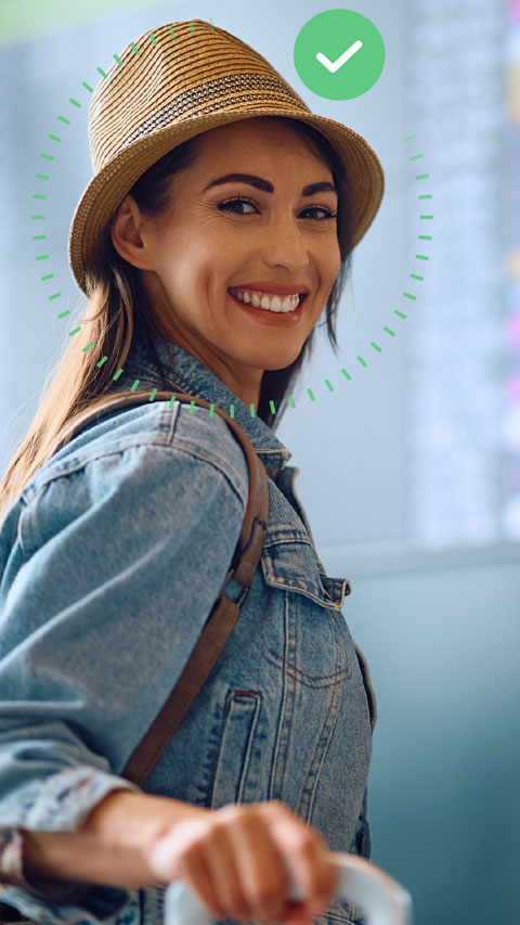 Viajera sonriente mira a cámara. Un check verde superpuesto indica que ha realizado el check-in online