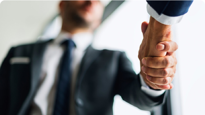 Handshake shot from below, with one person blurred in the background