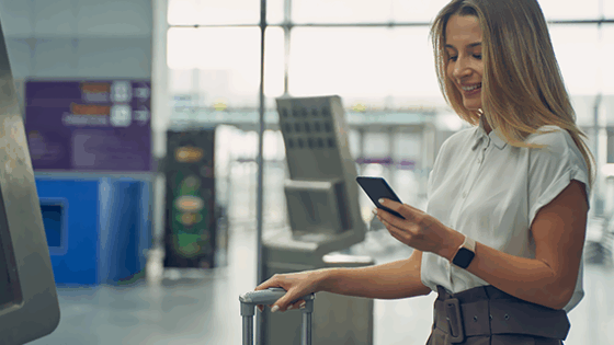 Pasajera en un aeropuerto consultando en el móvil la tarjeta de embarque