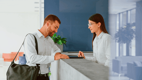 Un hombre hace el checking en un hotel frente a la recepcionista