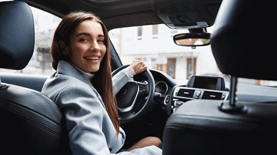 Una mujer al volante, sonríe a la camara