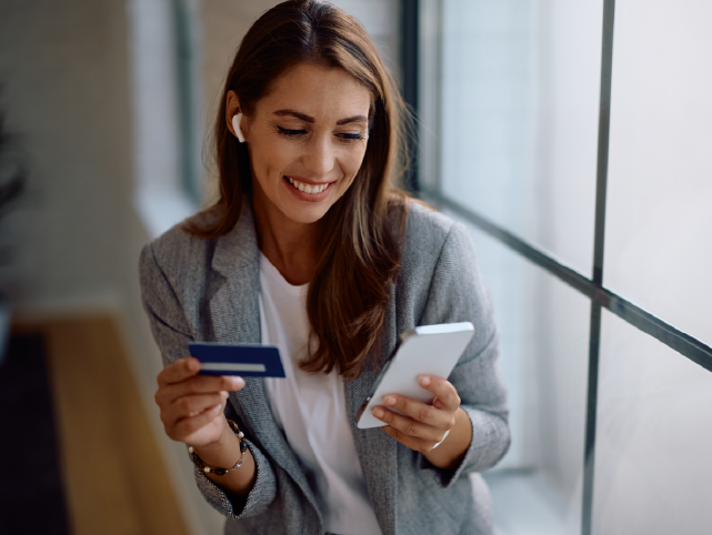 Cartão de crédito em uma mão, celular na outra