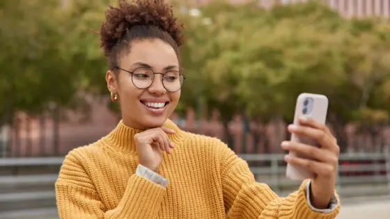 Chica positiva de pelo rizado crea contenido de selfies con su smartphone