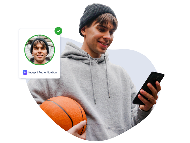 Joven con pelota de basket en una mano y teléfono móvil, con el que ha hecho una autenticación exitosa, en la otra