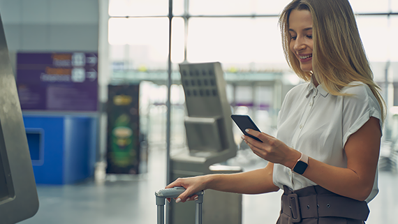 Pasajera en un aeropuerto consultando en el móvil la tarjeta de embarque