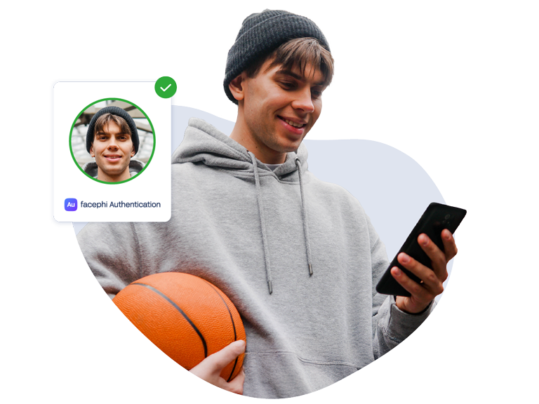 Joven con pelota de basket en una mano y teléfono móvil, con el que ha hecho una autenticación exitosa, en la otra